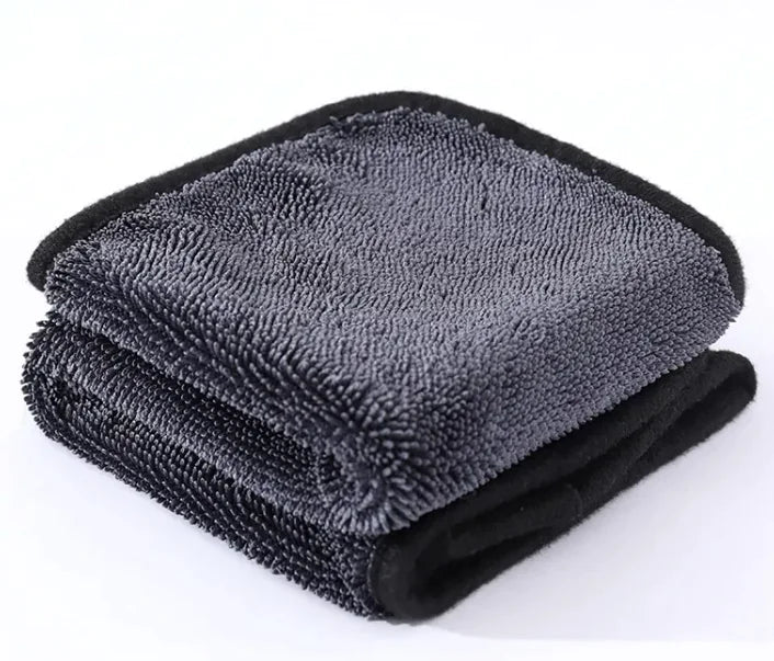 Folded gray microfiber towel with black edges on a white background
